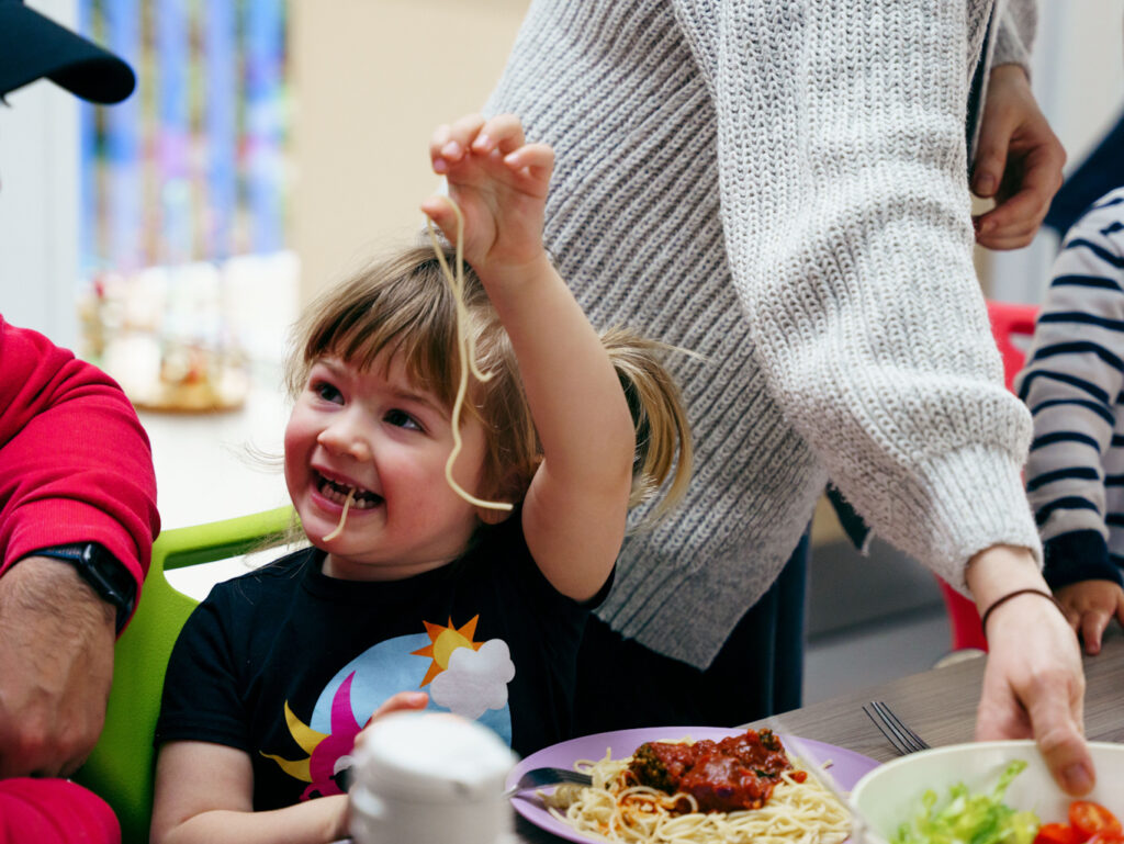 A young girl enjoying homemade spaghetti at a Healthy Living Platform event