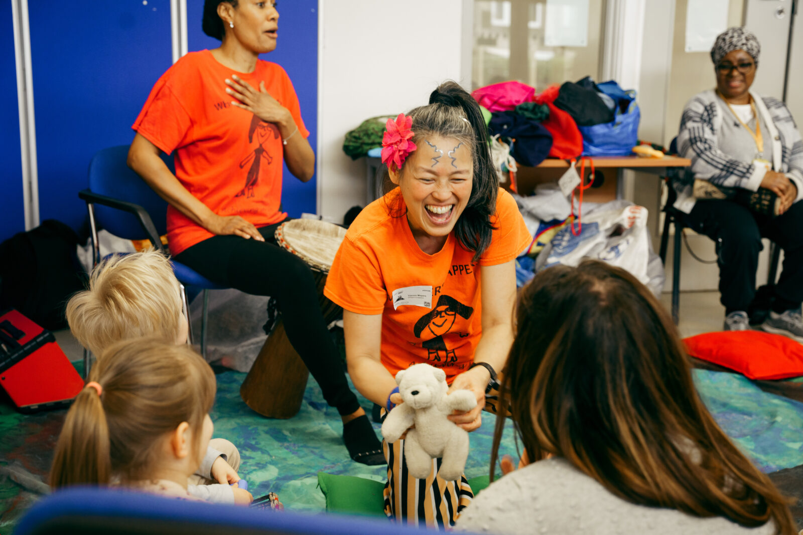 A member of the Whippersnappers team using a small teddy bear to interact with early years children